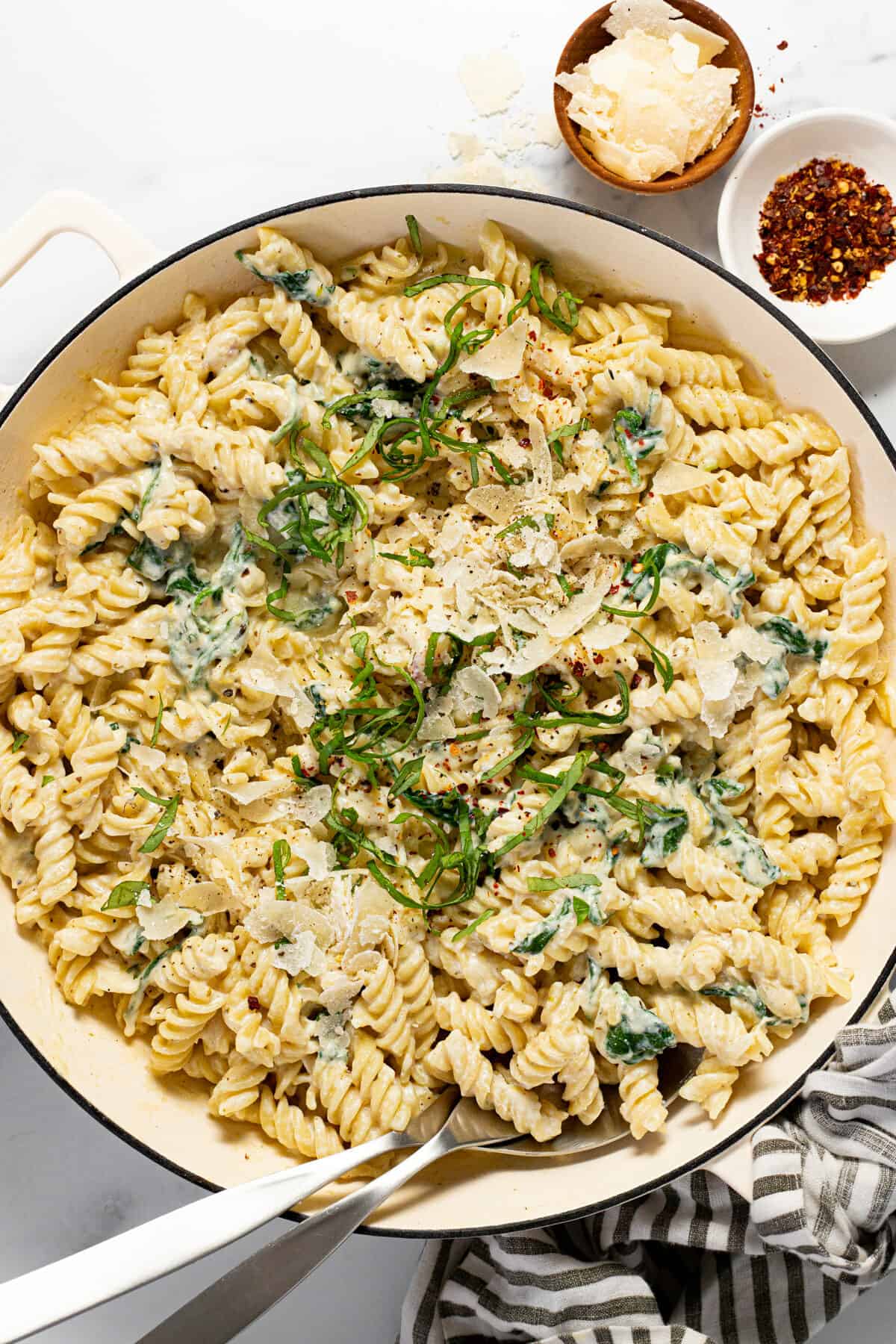 Large pan filled with lemon ricotta pasta garnished with Parmesan cheese and fresh basil.