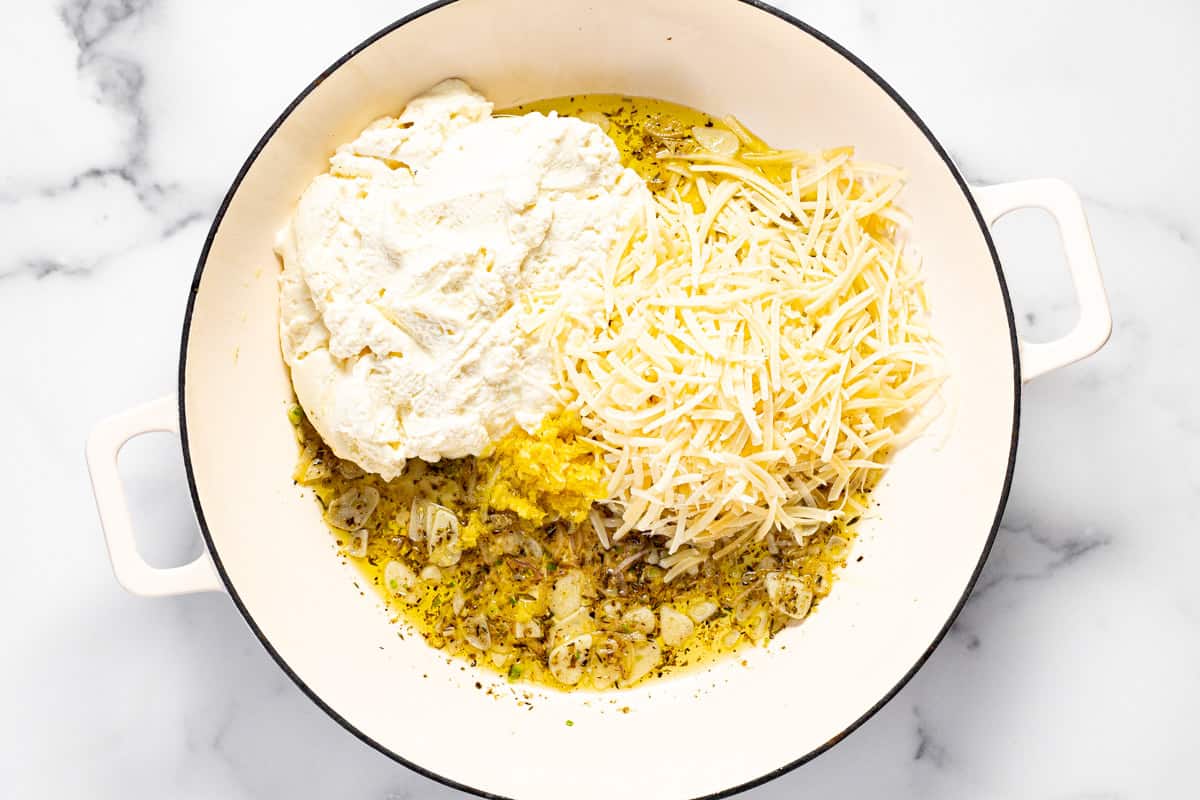 Large sauté pan with sauteed garlic and herbs, ricotta cheese, lemon zest, and Parmesan cheese.