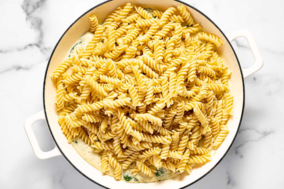Large white pan filled with rotini pasta and creamy ricotta sauce.