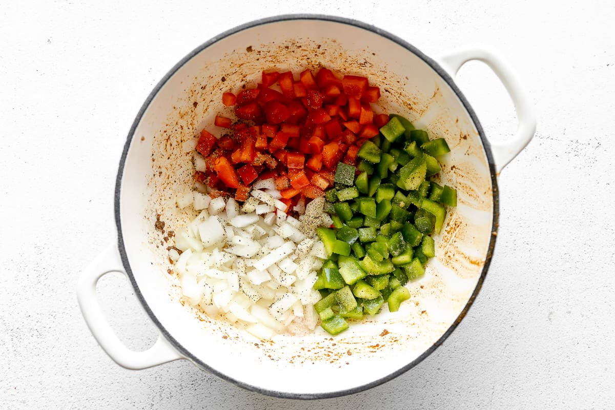 Diced onion and bell pepper in a large white pan.