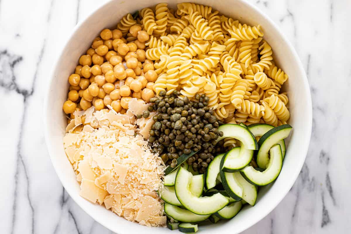 White bowl filled with ingredients to make Caesar kale pasta salad.