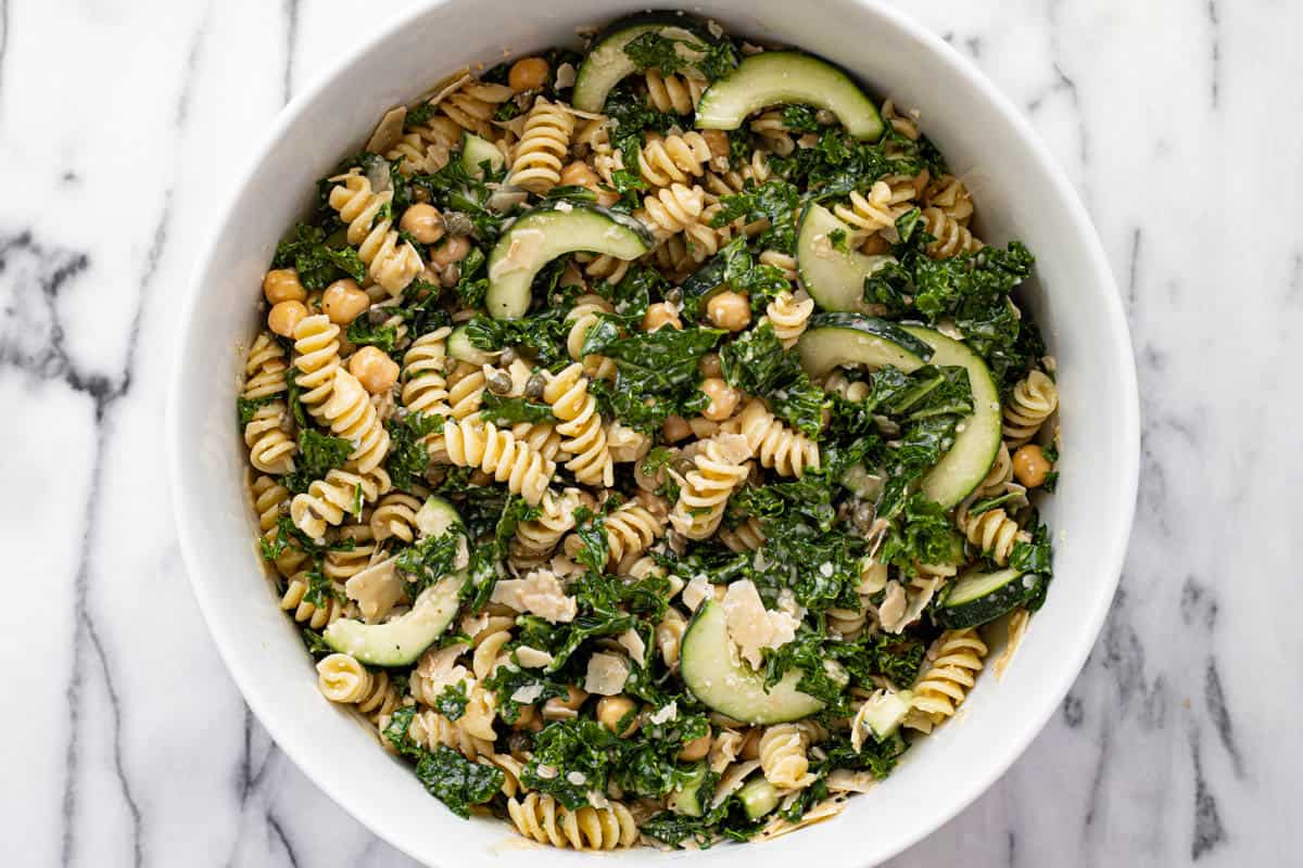 White bowl filled with homemade kale Caesar pasta salad. 