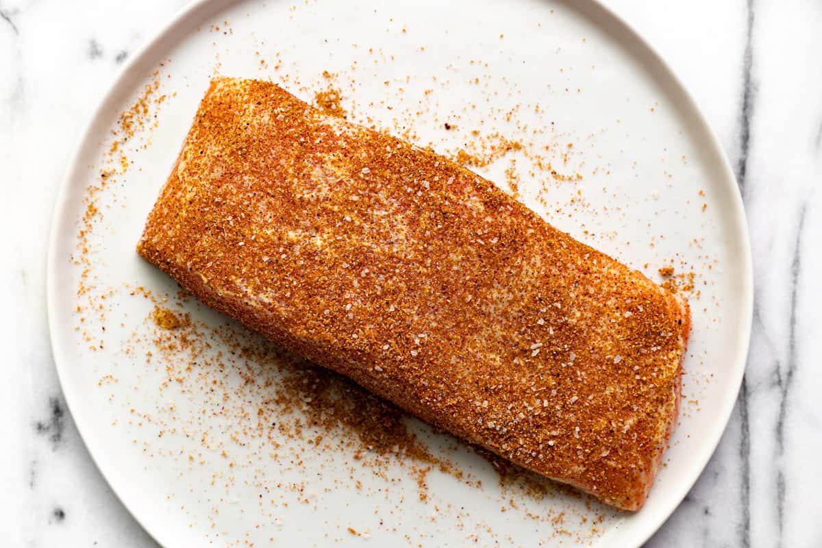 A fillet of salmon seasoned with mustard and dry rub.