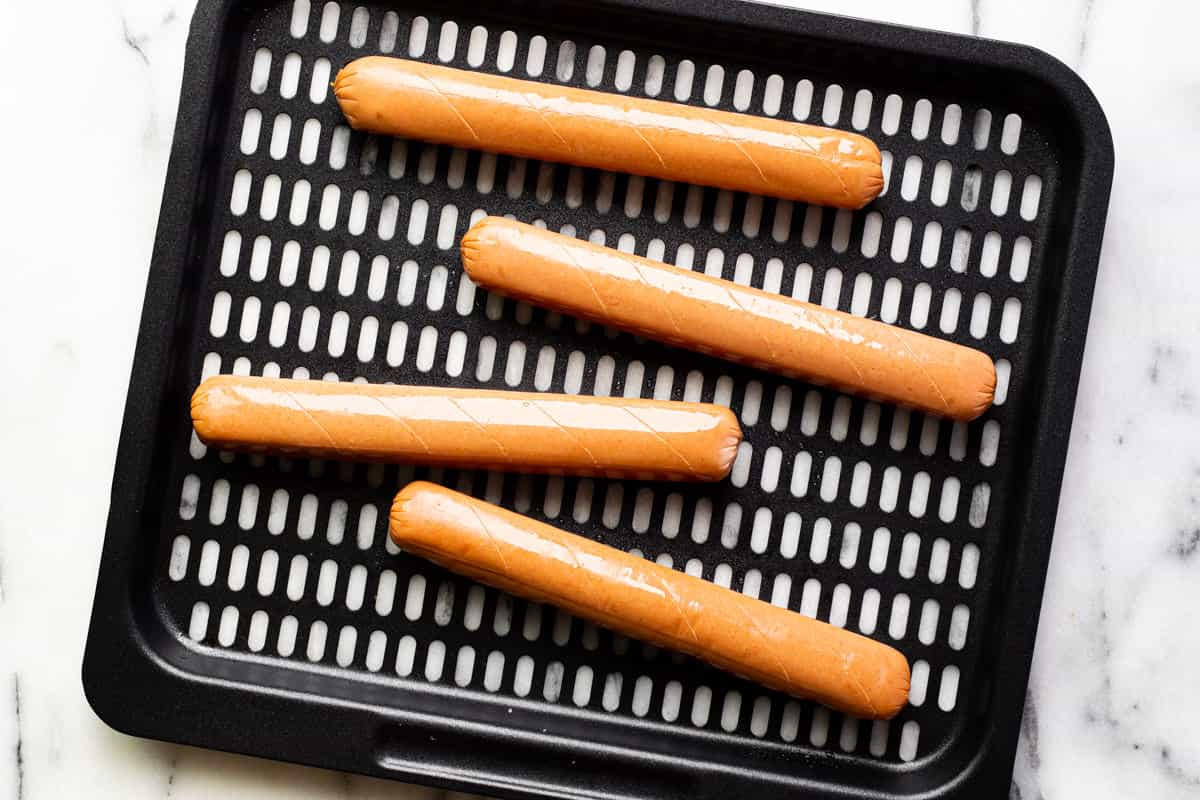 4 hot dogs on an air fryer tray.
