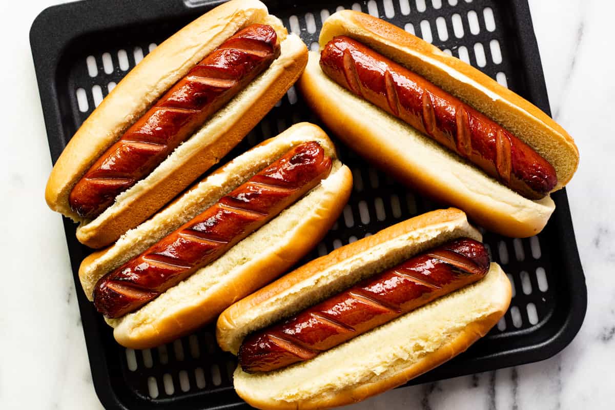 4 hot dogs in buns on an air fryer tray.