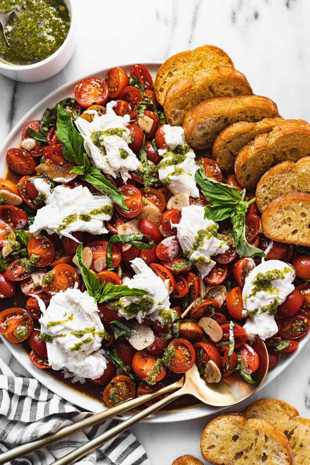 Large white plate with sliced tomatoes and burrata salad with crostini.