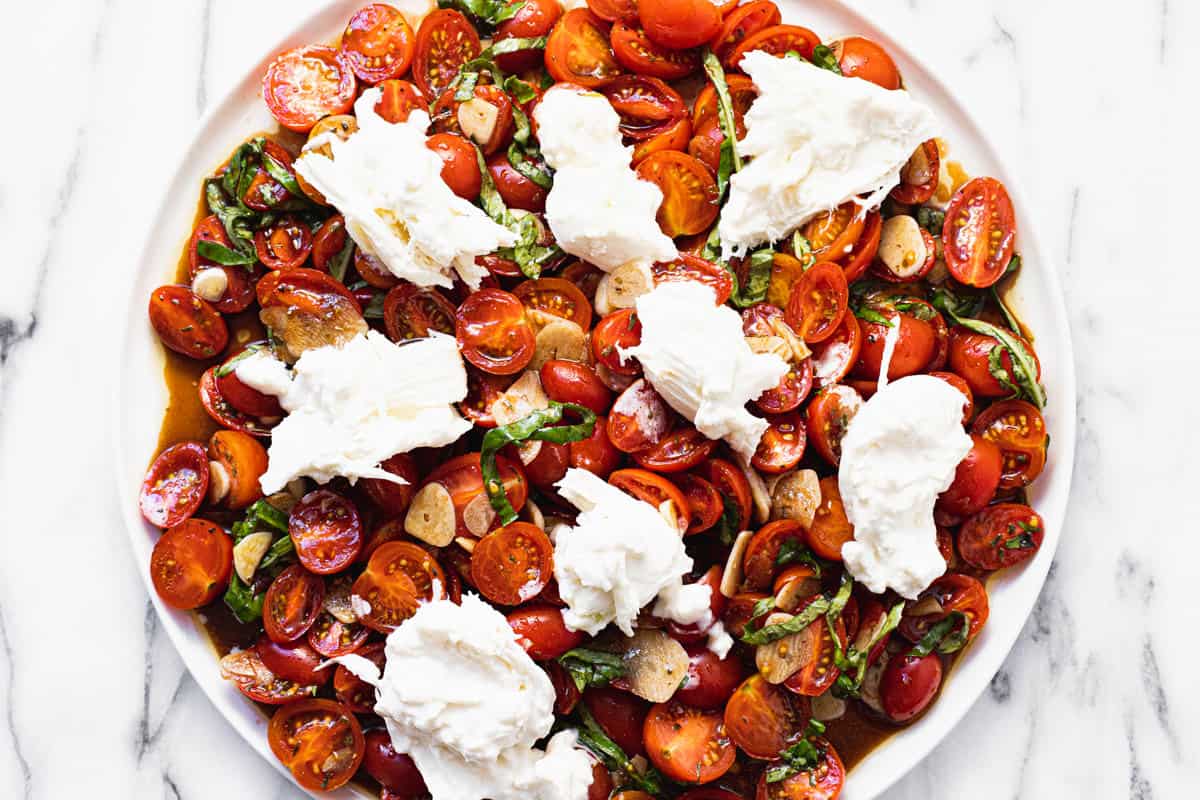 Tomato salad topped with torn burrata cheese.