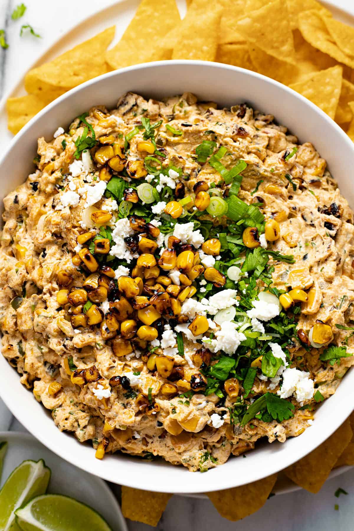 White bowl filled with creamy street corn dip garnished with cilantro and Cotija cheese.