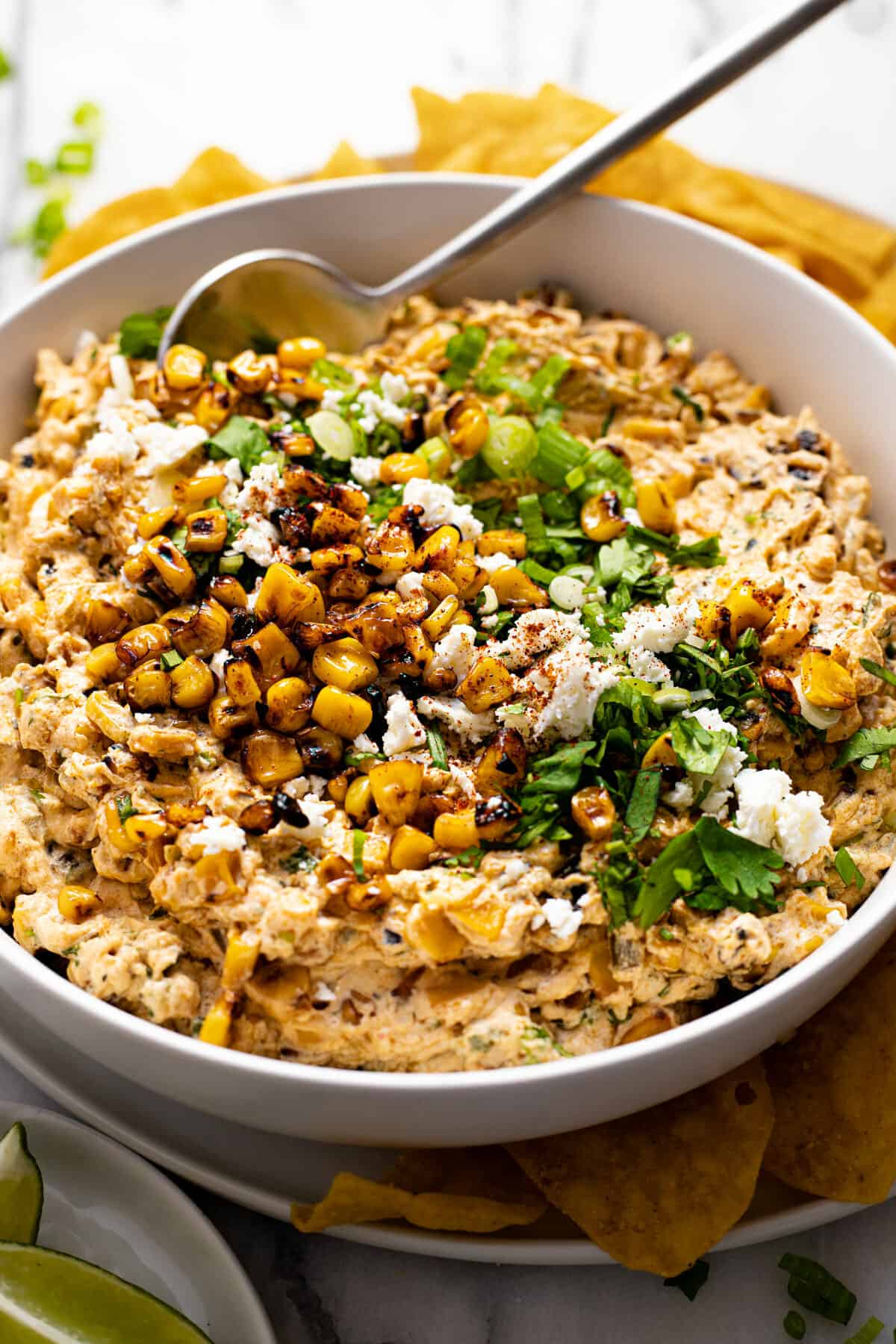 White bowl filled with creamy street corn dip garnished with cilantro and Cotija cheese.