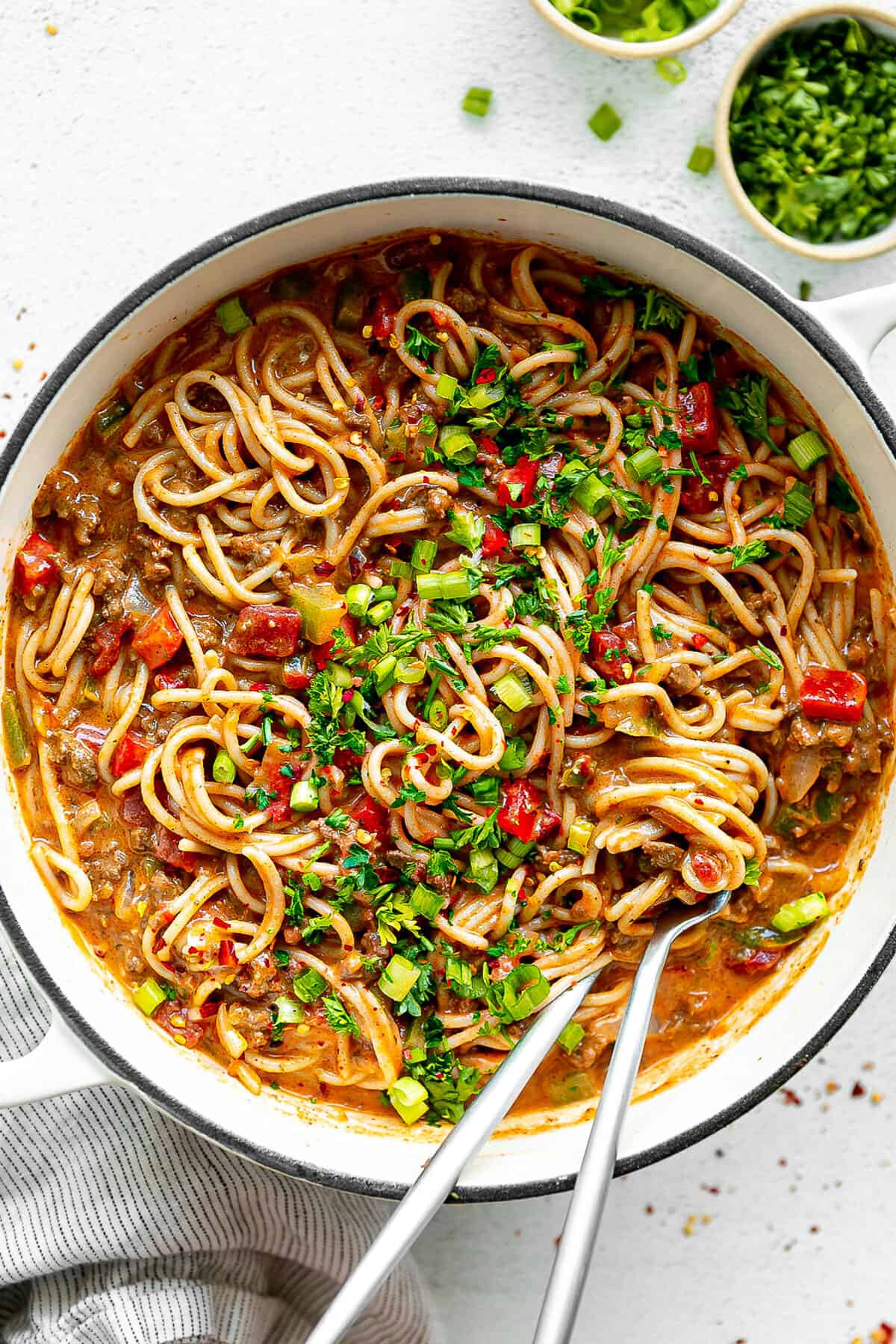 Large white pot filled with taco spaghetti garnished with cilantro and green onion.