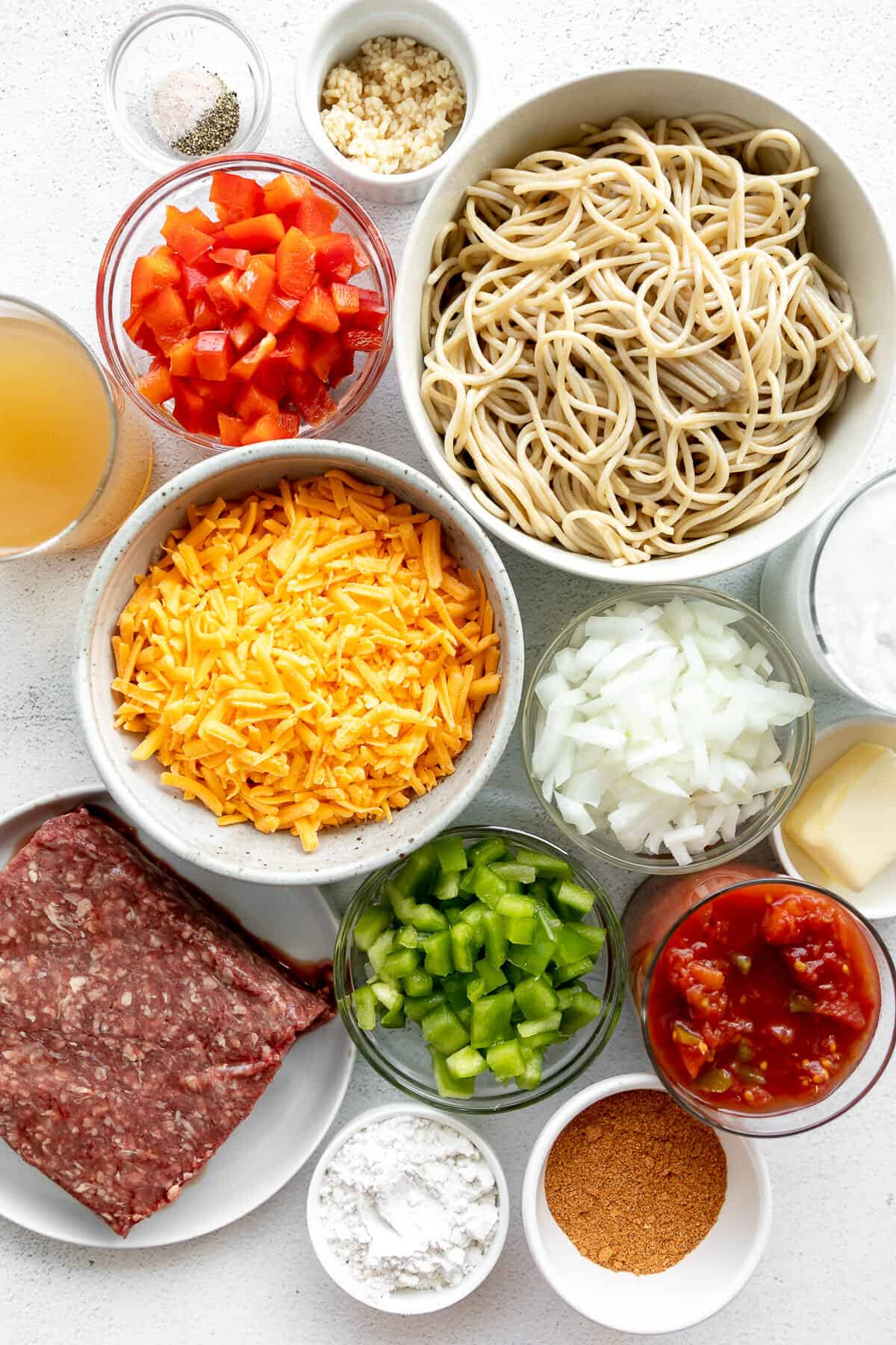 White counter top with bowls of ingredients to make creamy taco pasta.