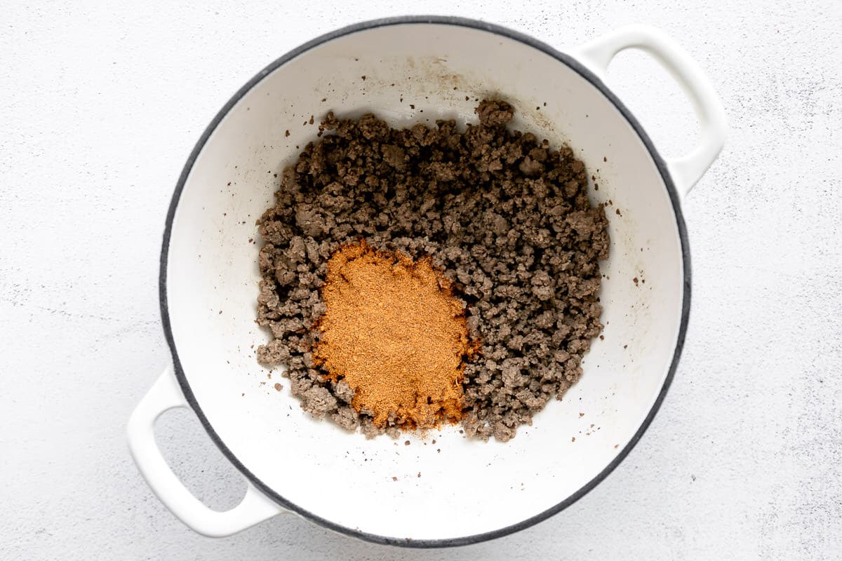 Taco seasoning added to a pot of cooked ground beef.
