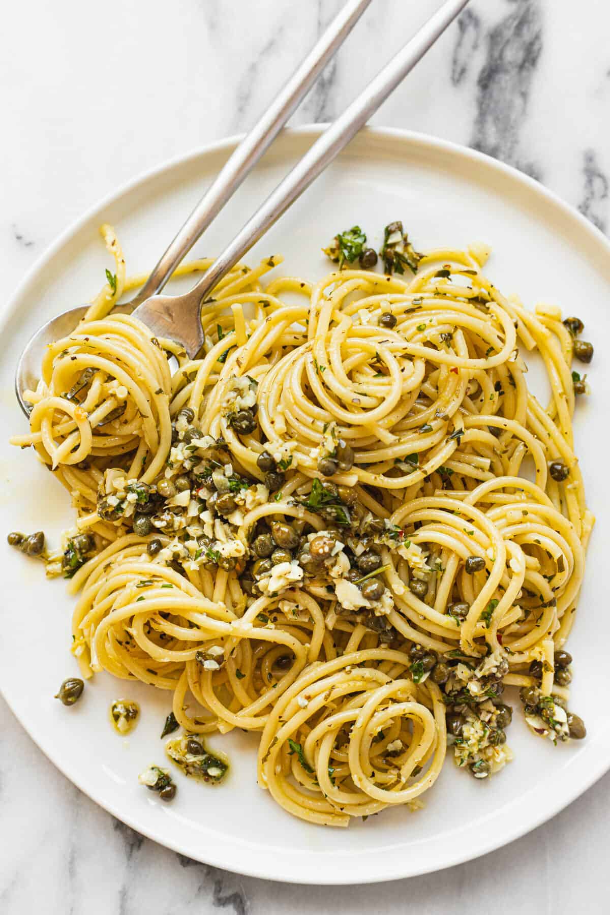 Lemon garlic spaghetti with capers on a large white plate.