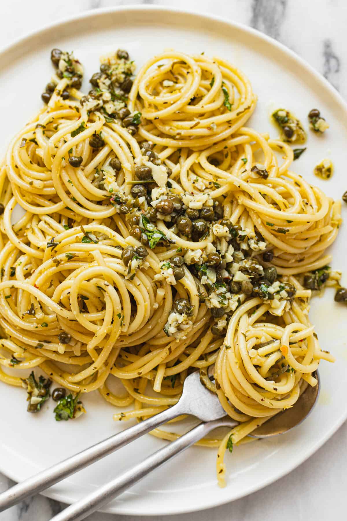 Lemon garlic spaghetti with capers on a large white plate.