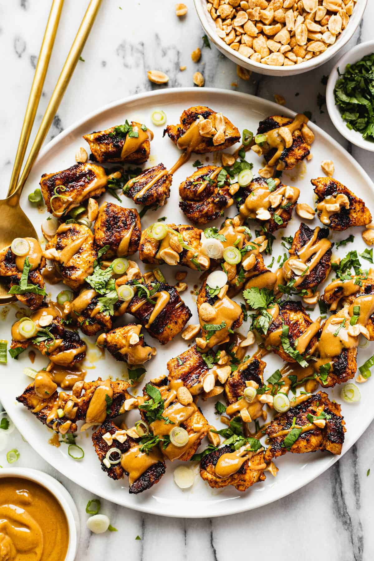 Large white platter filled with seared peanut butter chicken drizzled with peanut sauce.