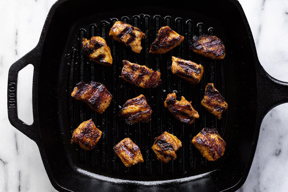 Cast iron pan filled with grilled peanut butter chicken.