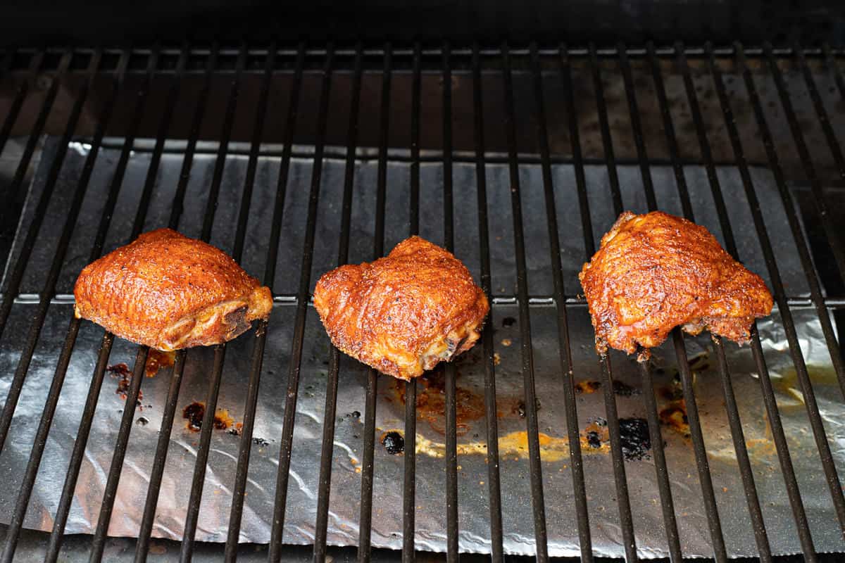 Smoked chicken thighs on a grill grate.