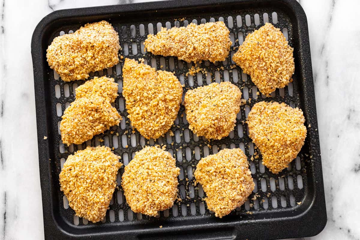 Breaded chicken pieces on an air fryer tray.