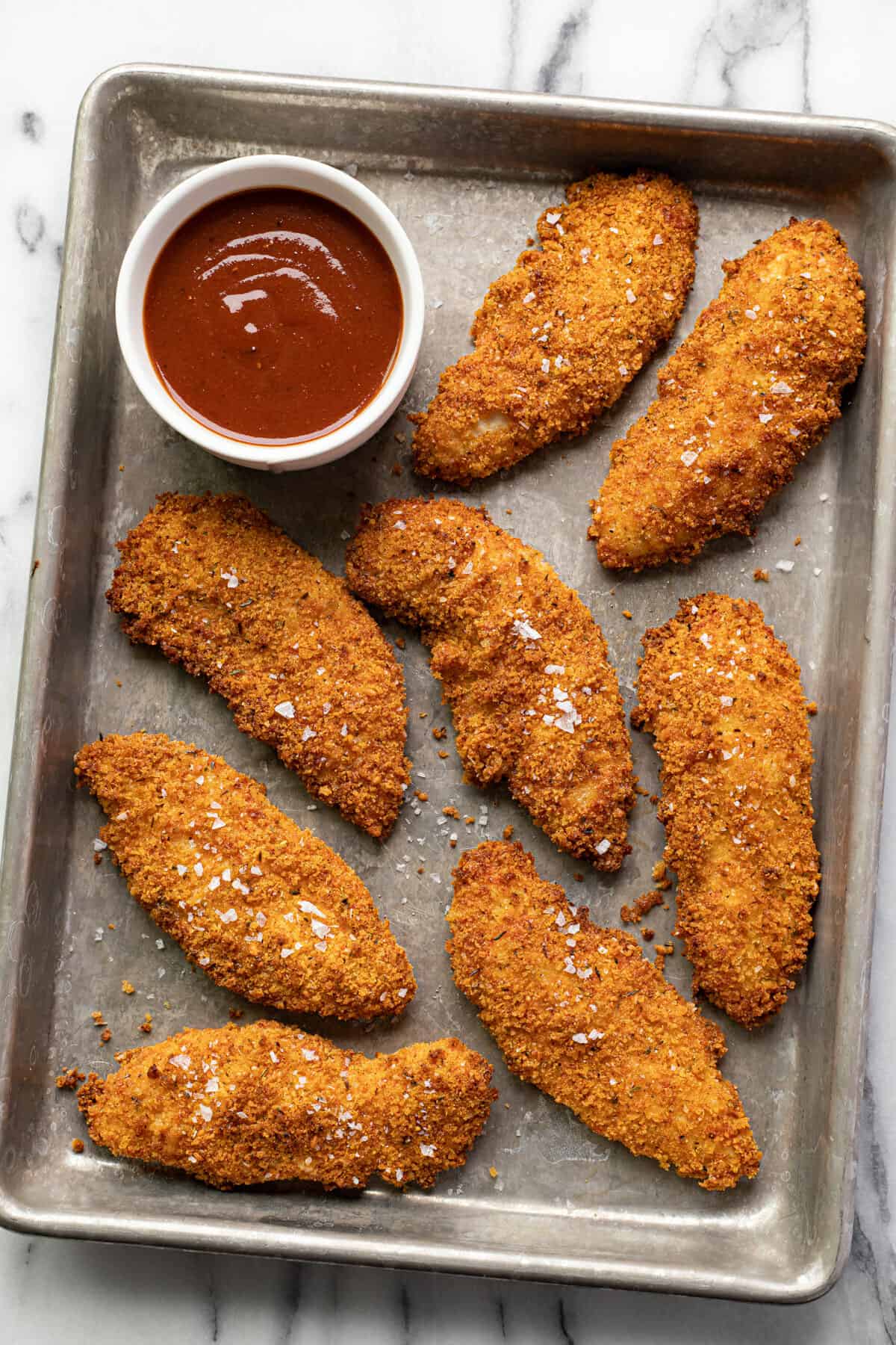 Freshly cooked air fryer chicken tenders on a small metal baking sheet.