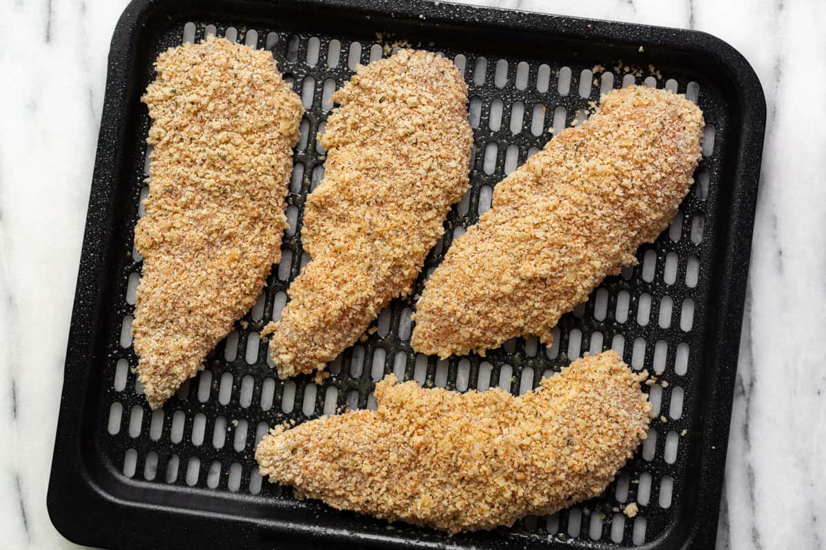Air fryer chicken tenders on an air fryer tray ready to go in the air fryer.