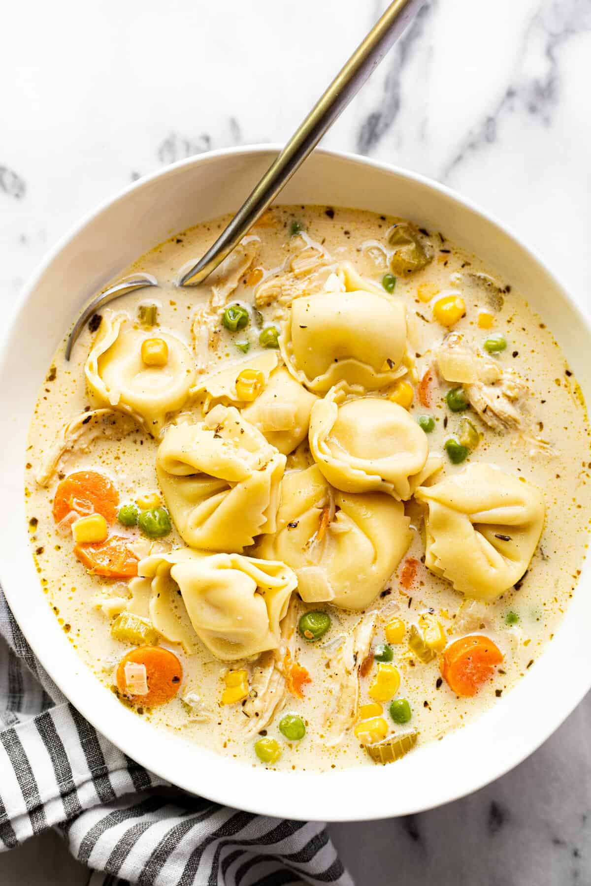 White bowl filled with homemade chicken tortellini soup.