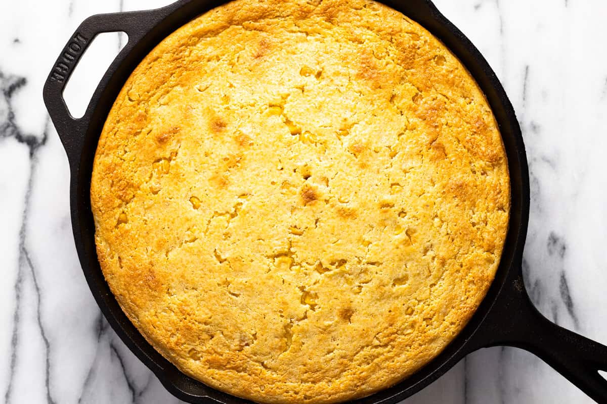Large cast iron pan filled with freshly baked cornbread casserole.