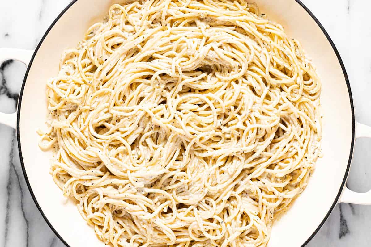 Large white pan filled with spaghetti tossed in a lemon cream sauce.