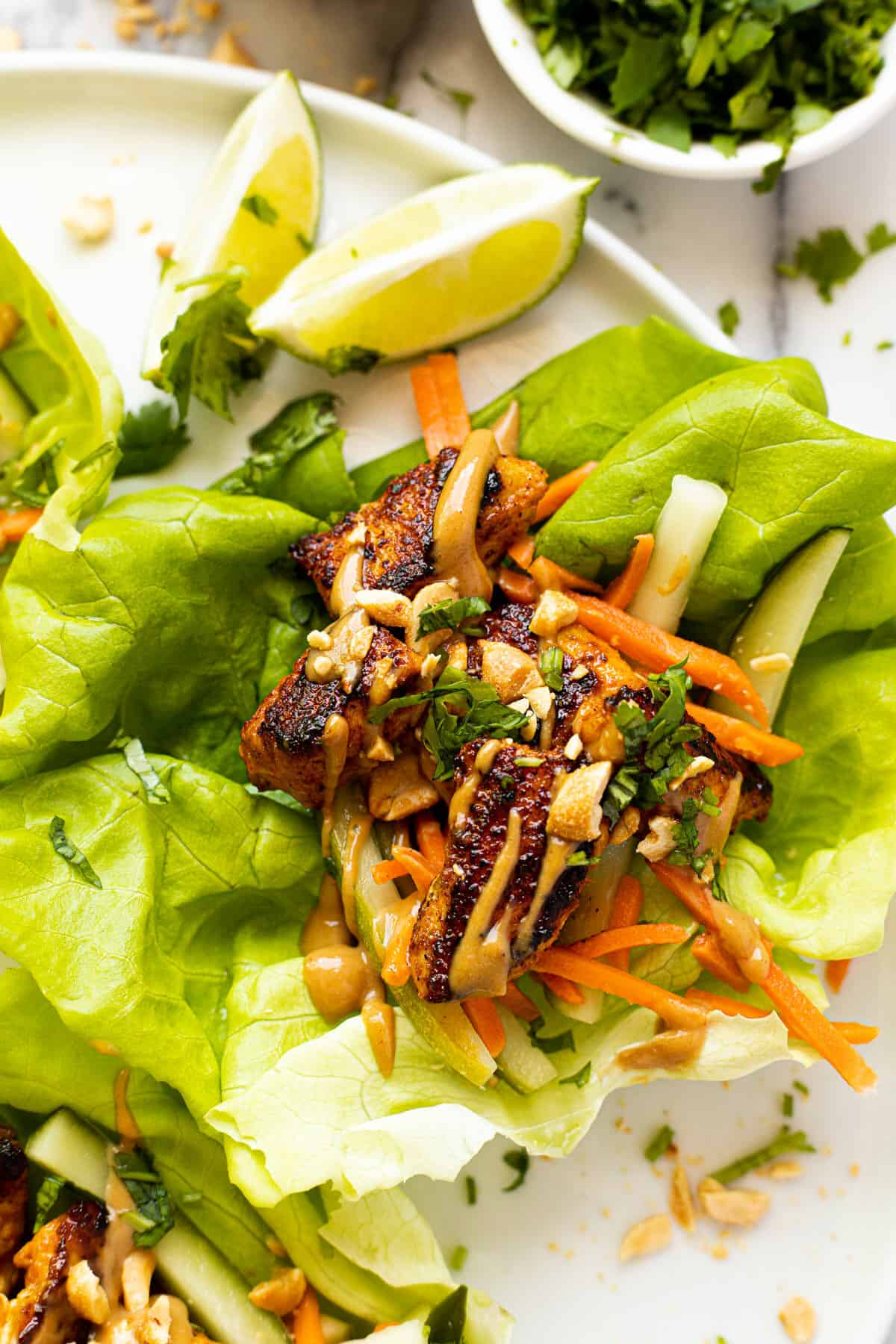Close up shot of a chicken lettuce wrap with pickled veggies and peanut sauce.