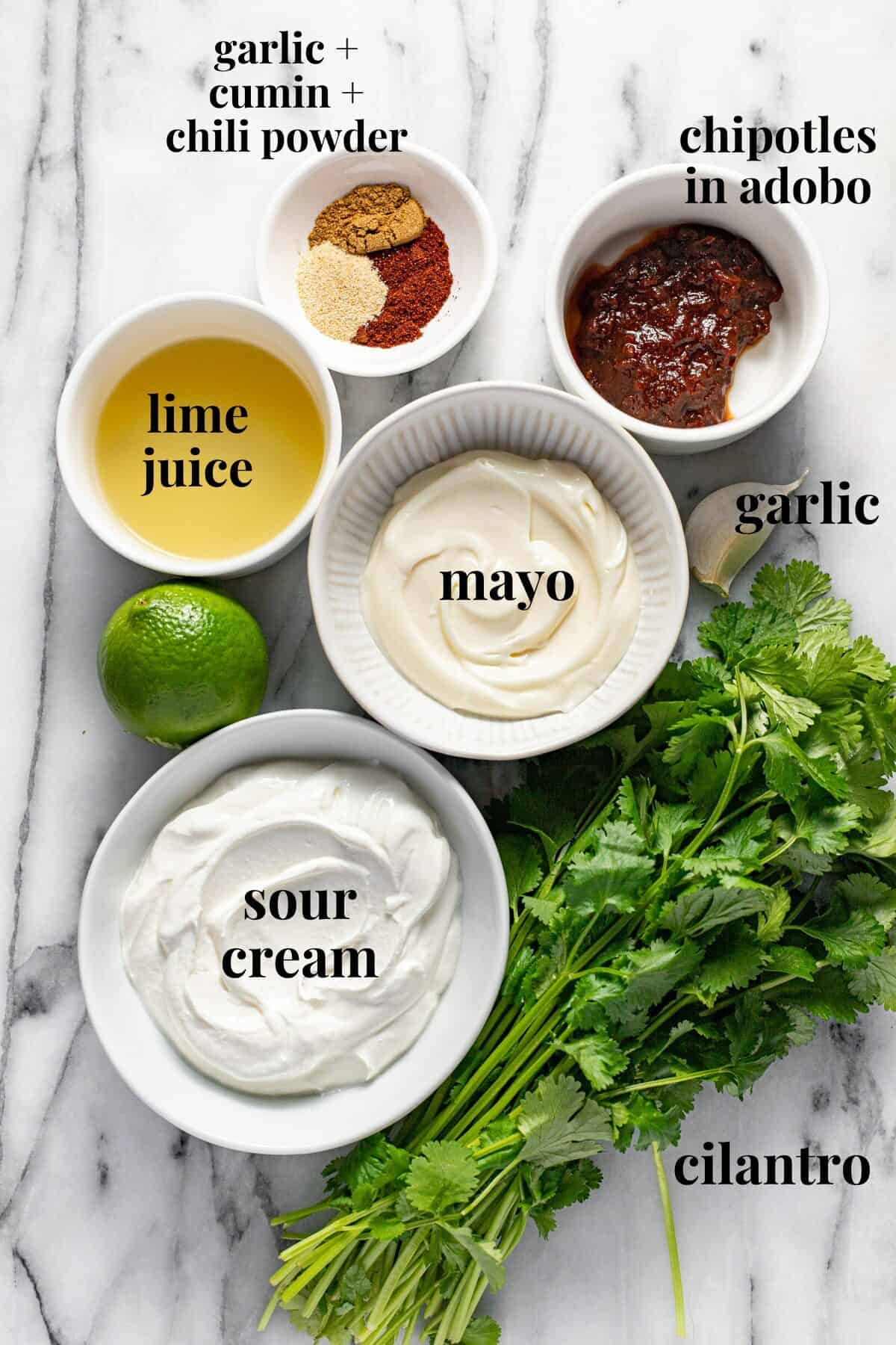 White marble counter top with bowls of ingredients to make chipotle sauce.