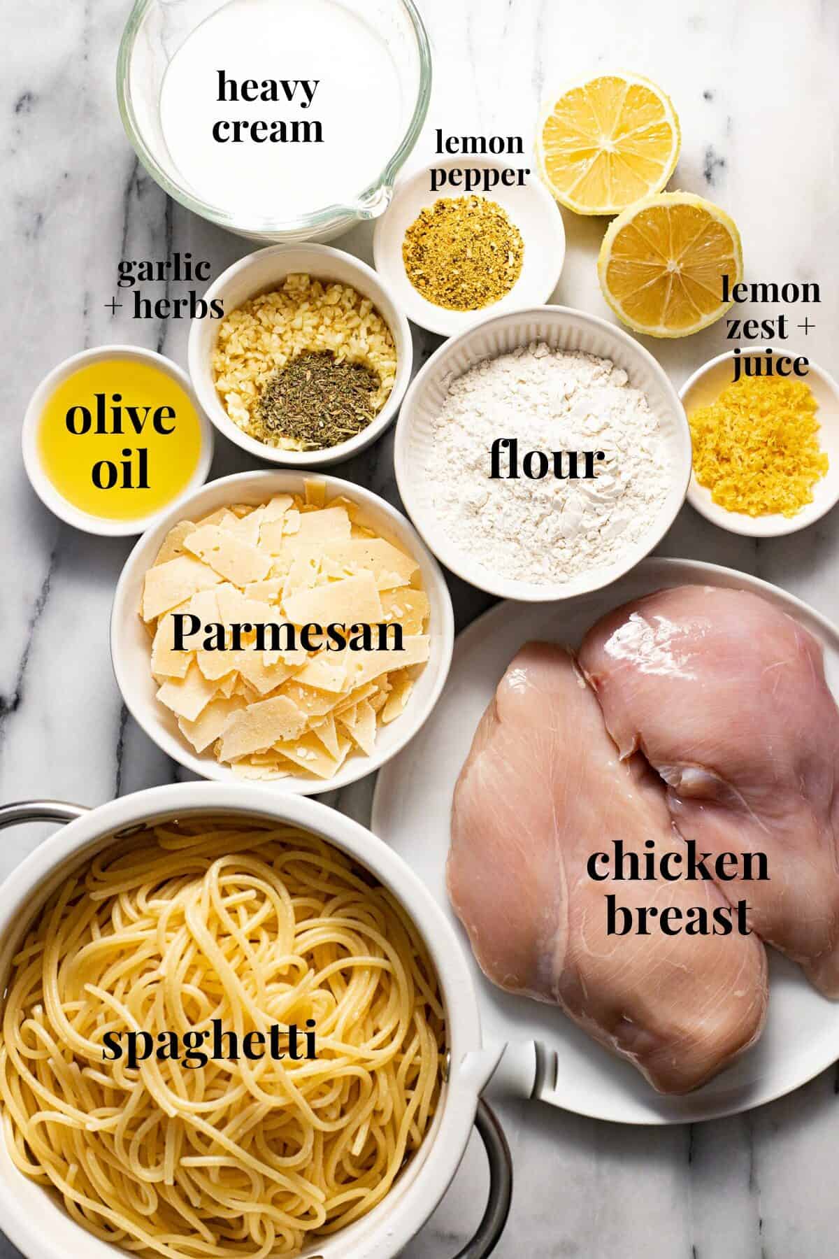 White marble counter top with bowls of ingredients to make creamy lemon chicken pasta.