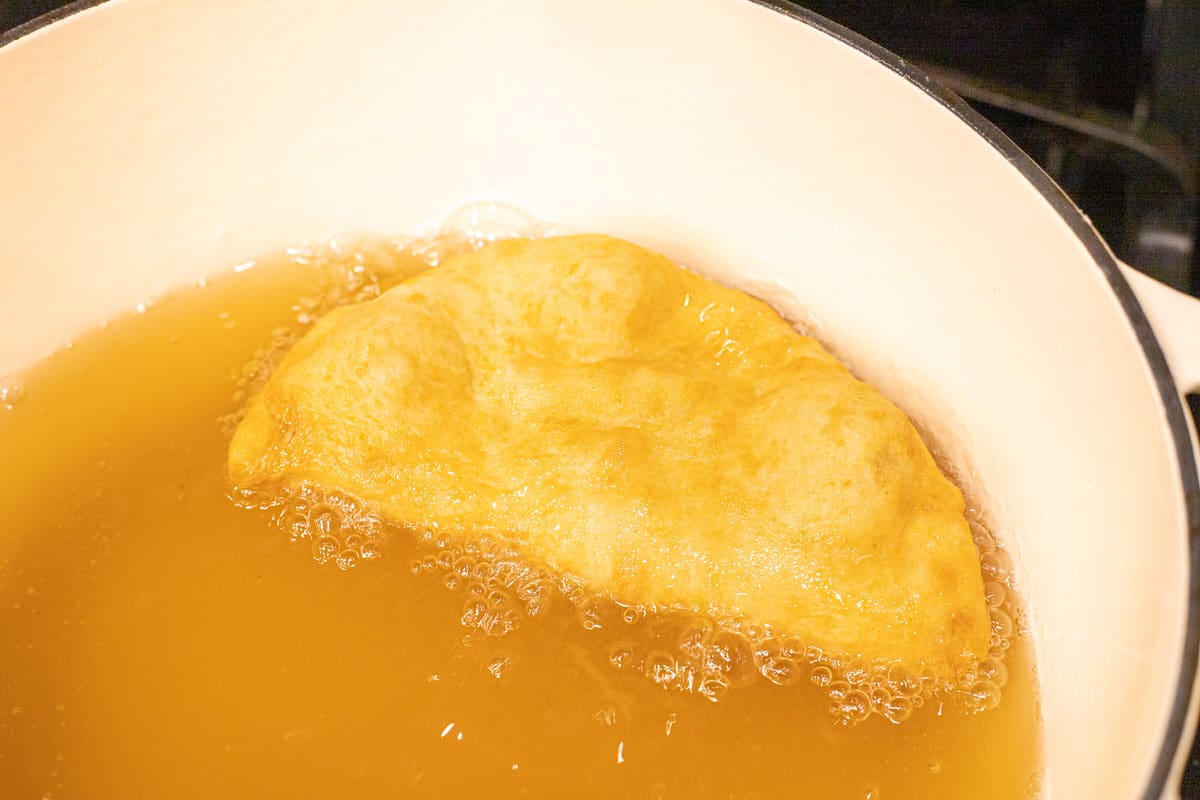 A chalupa shell frying in a large pot of oil.