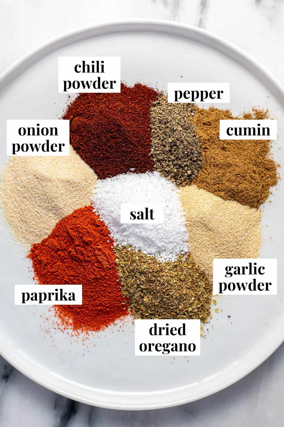 A white plate with small piles of spices on it to make homemade taco seasoning.