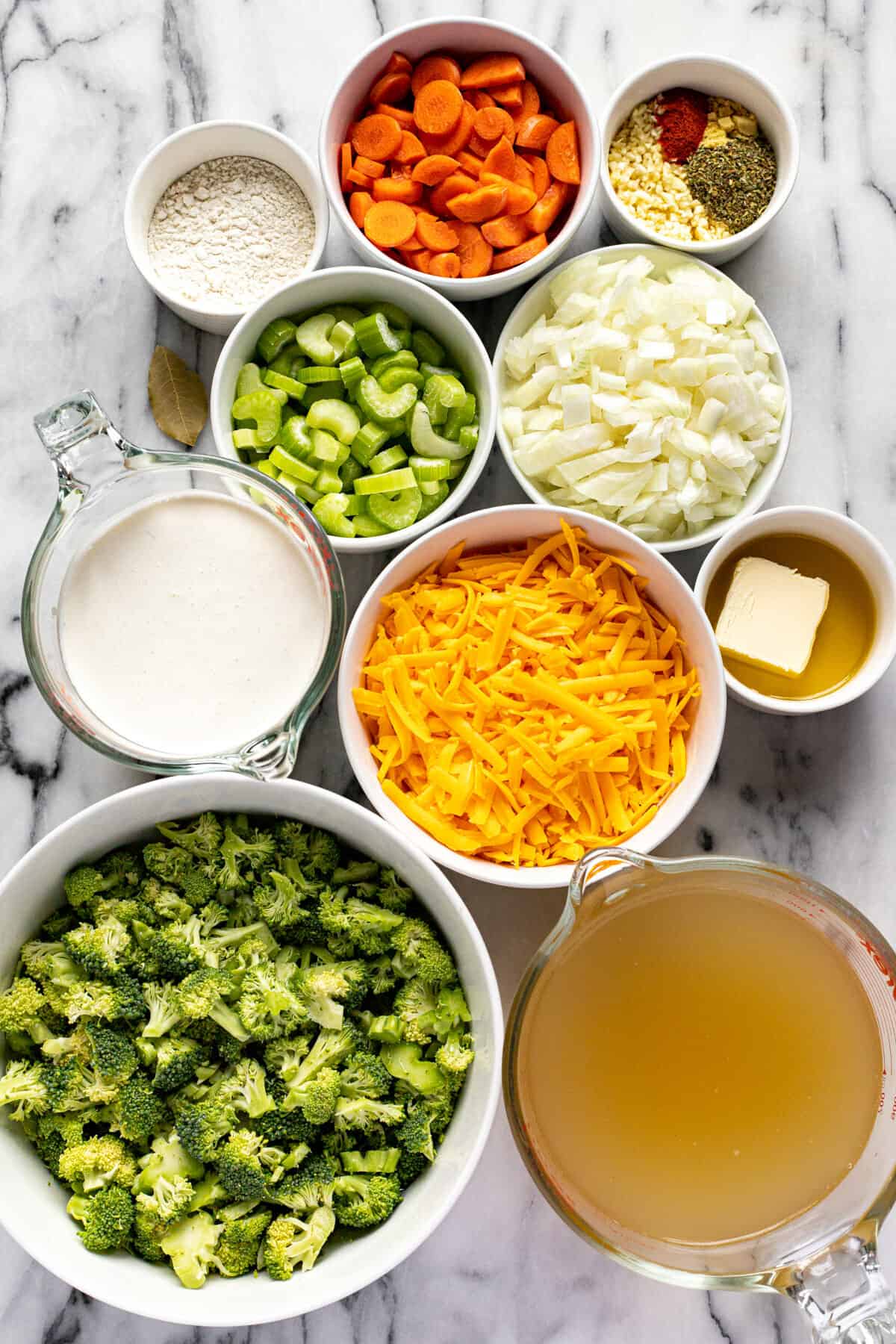 White marble counter top with bowls of ingredients to make instant pot broccoli cheese soup.