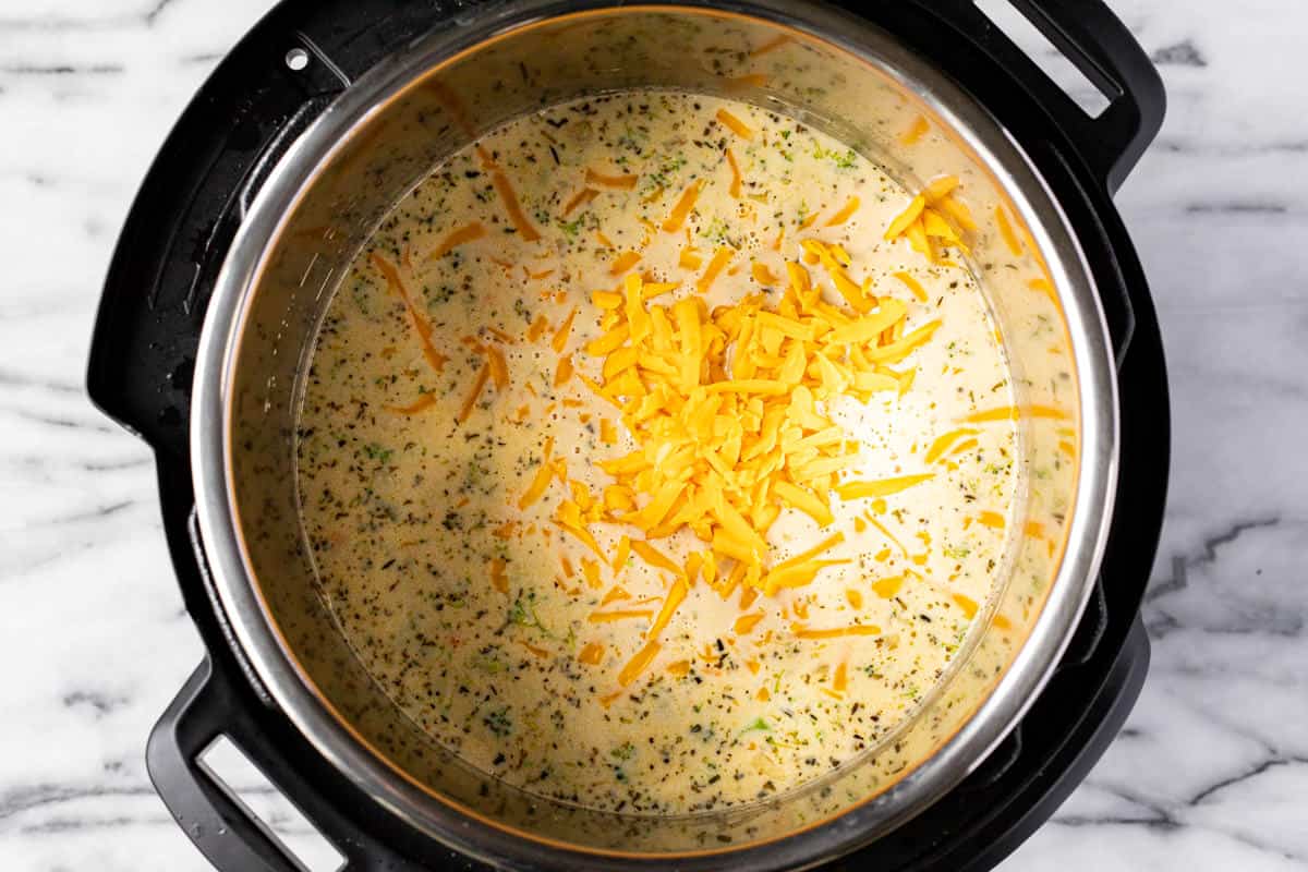 Instant pot filled with ingredients to make broccoli cheddar soup.