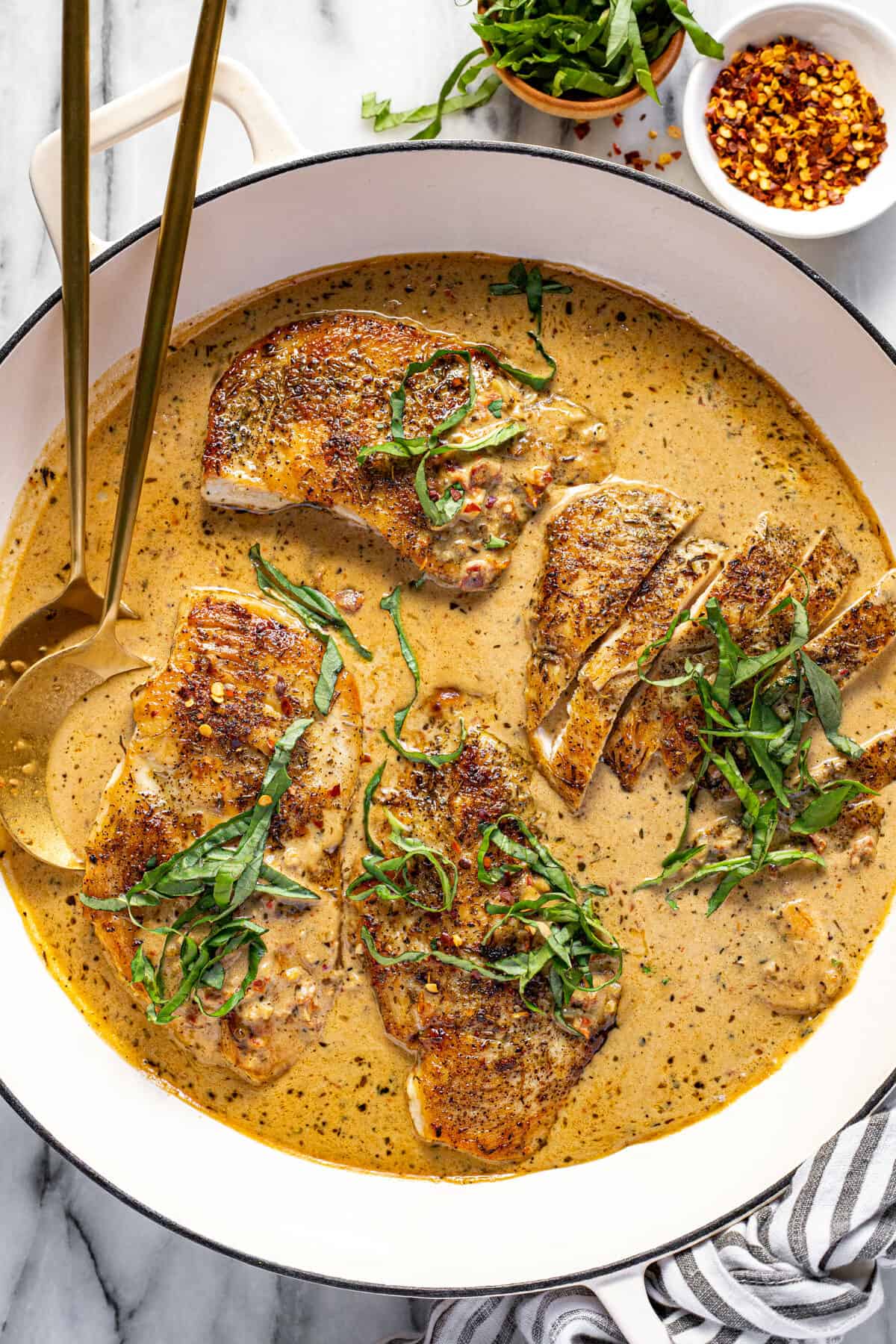 Large white pan filled with sauteed chicken and creamy sauce.