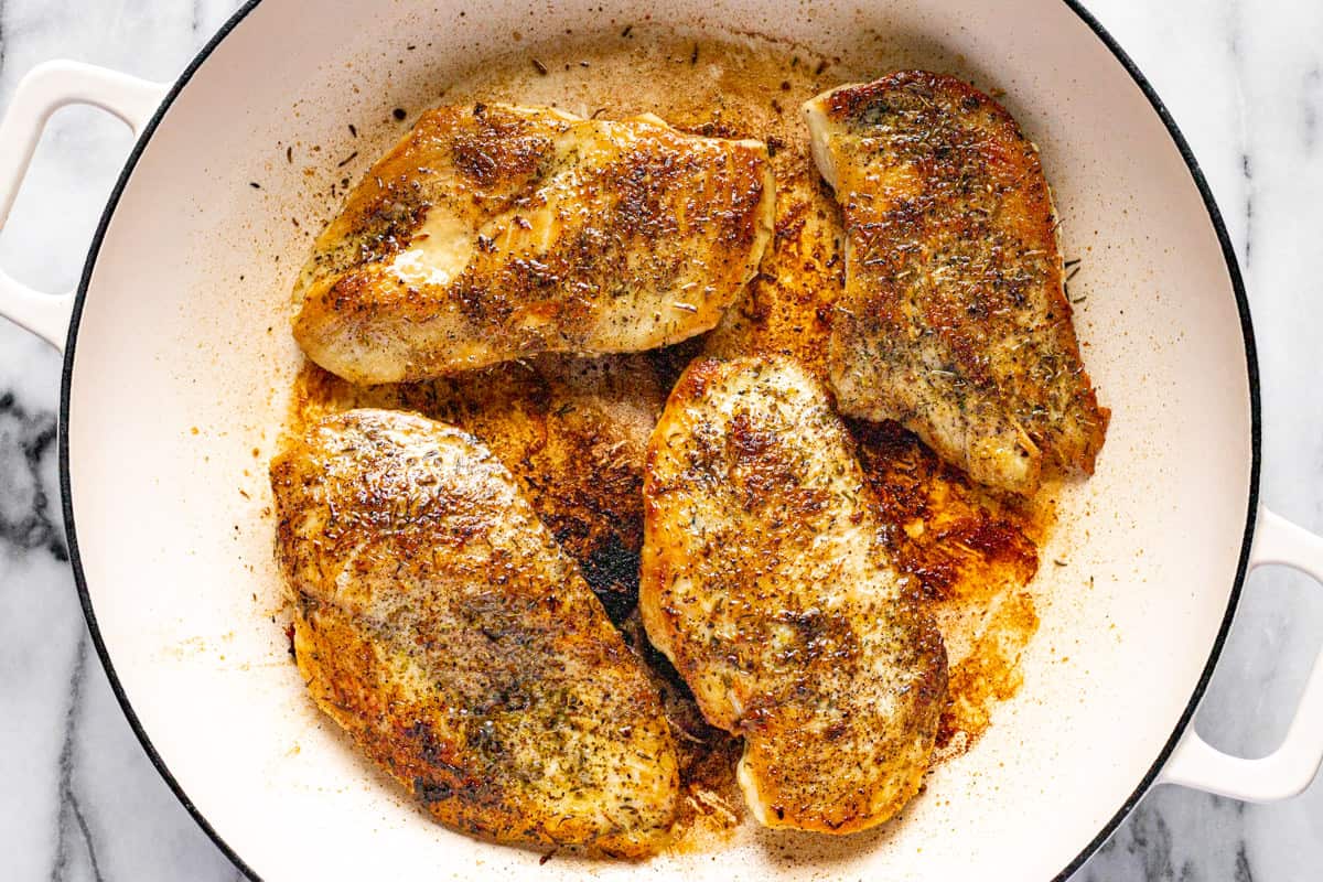Large white pan filled with sauteed chicken breast.