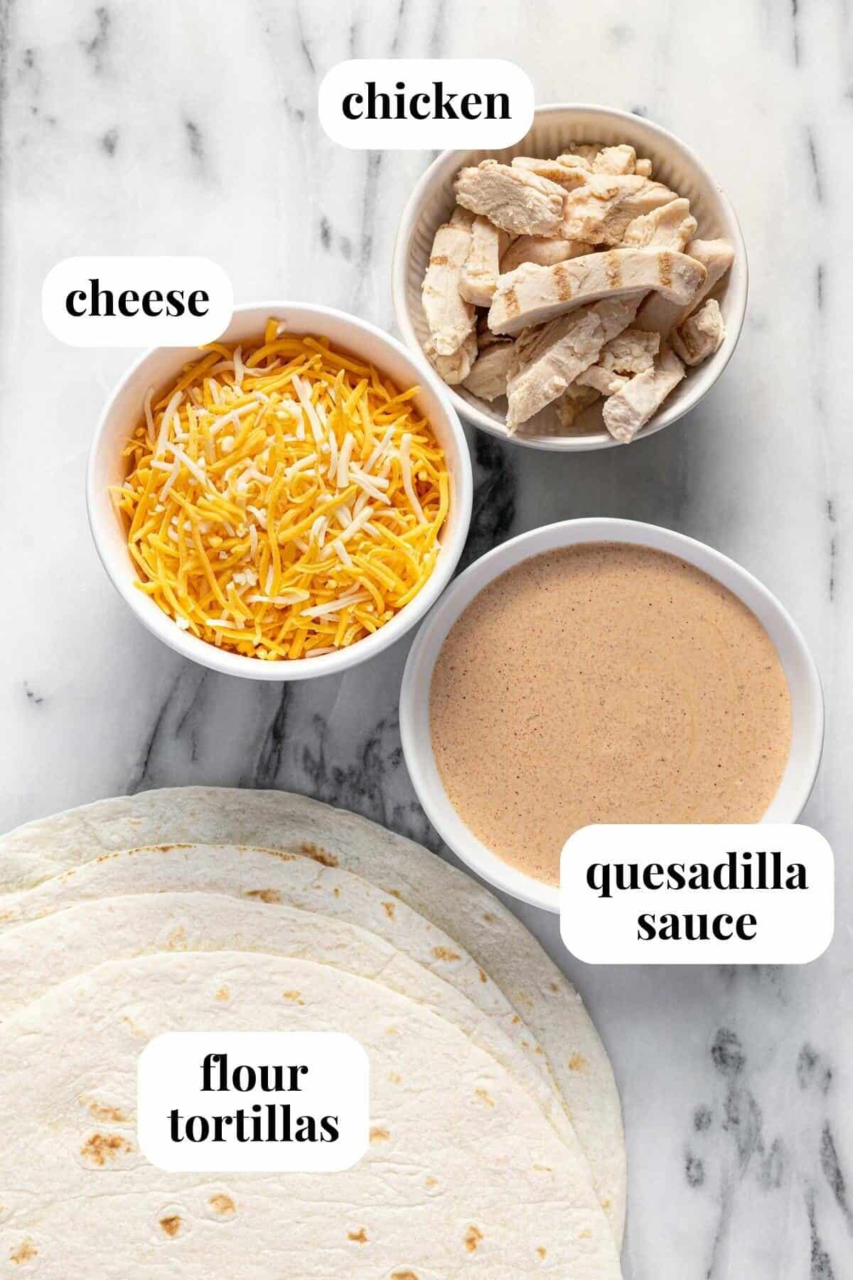 White marble counter top with bowls of ingredients to make chicken quesadillas.