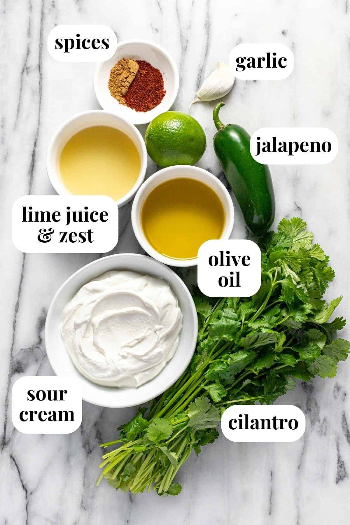 White marble counter top with bowls of ingredients to make cilantro lime sauce.