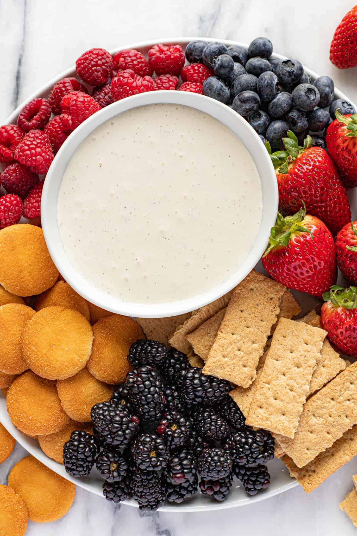 Platter of fruit, graham crackers, and Nilla wafers with a small bowl of fruit dip.