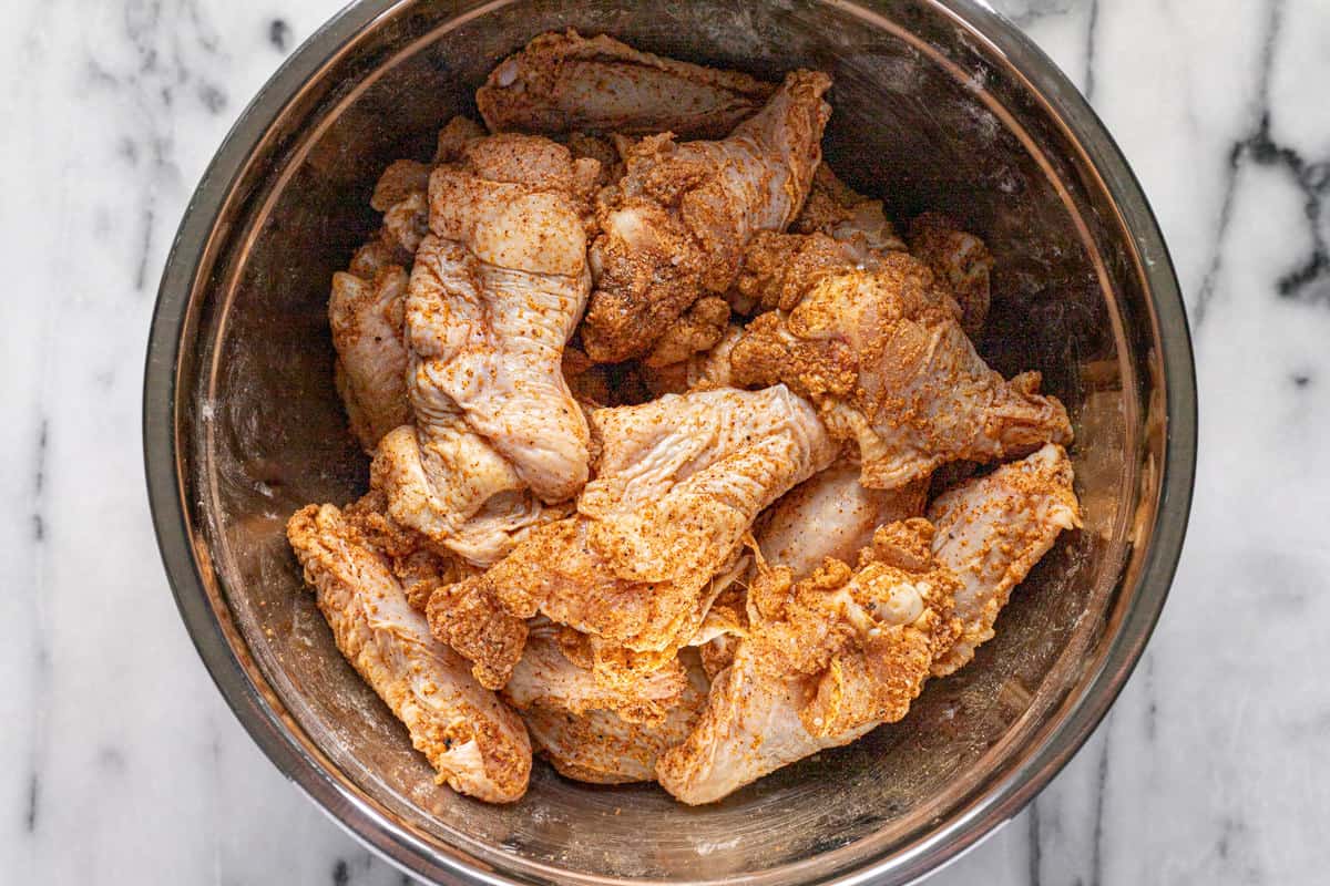 Medium metal bowl filled with seasoned chicken wings.