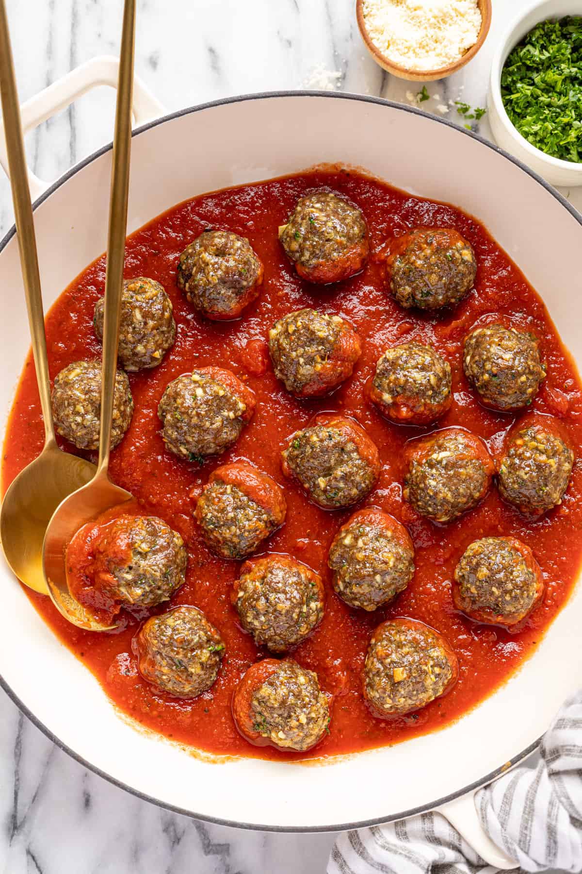 Large white pan filled with red sauce and homemade baked meatballs.