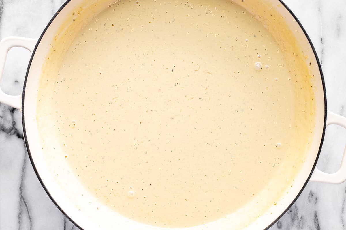 Creamy homemade alfredo sauce in a large white pan.