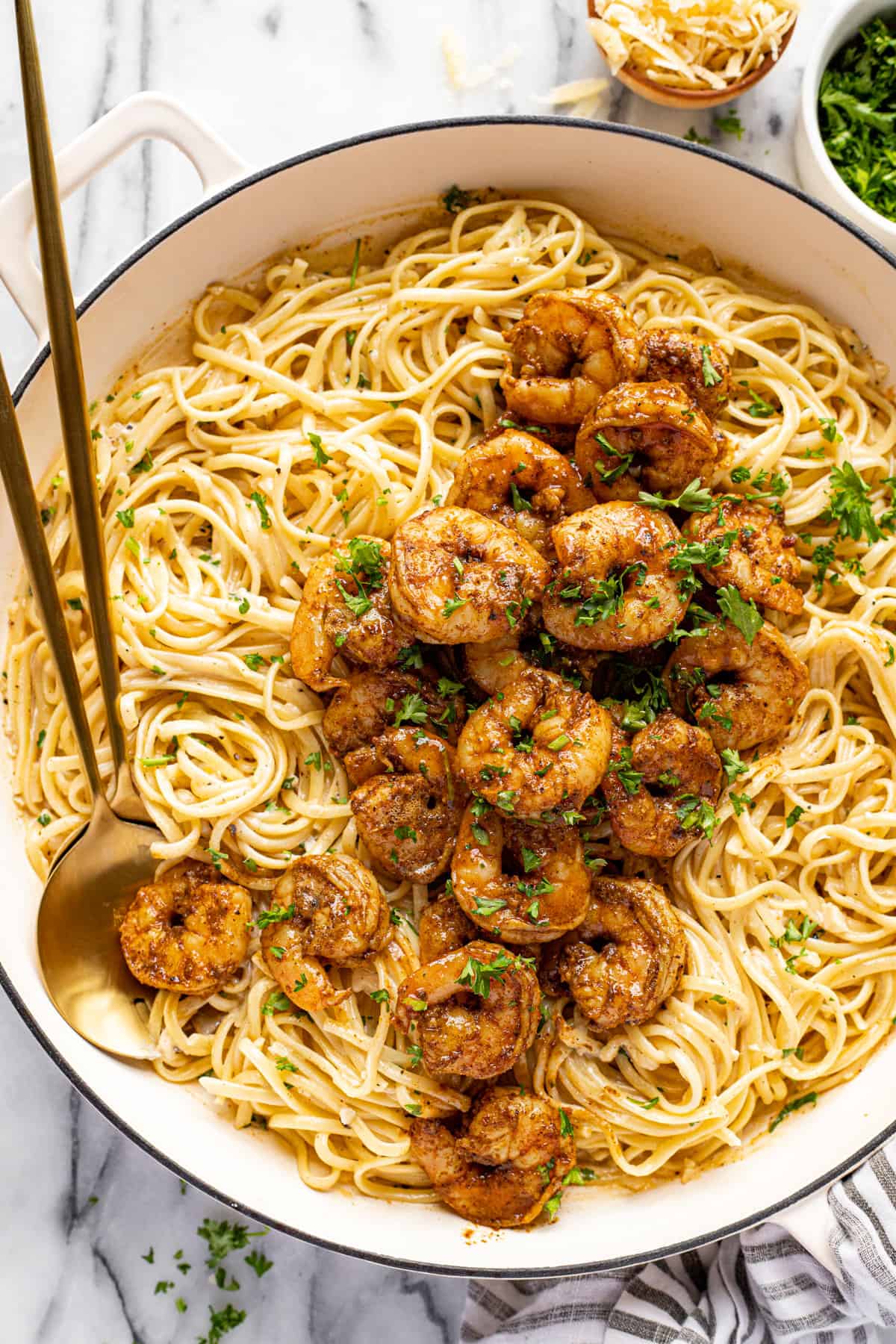 Large white pan filled with creamy Cajun shrimp pasta garnished with fresh parsley. 