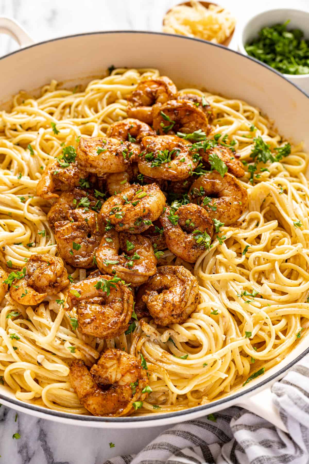 Large white pan filled with creamy Cajun shrimp pasta garnished with fresh parsley. 