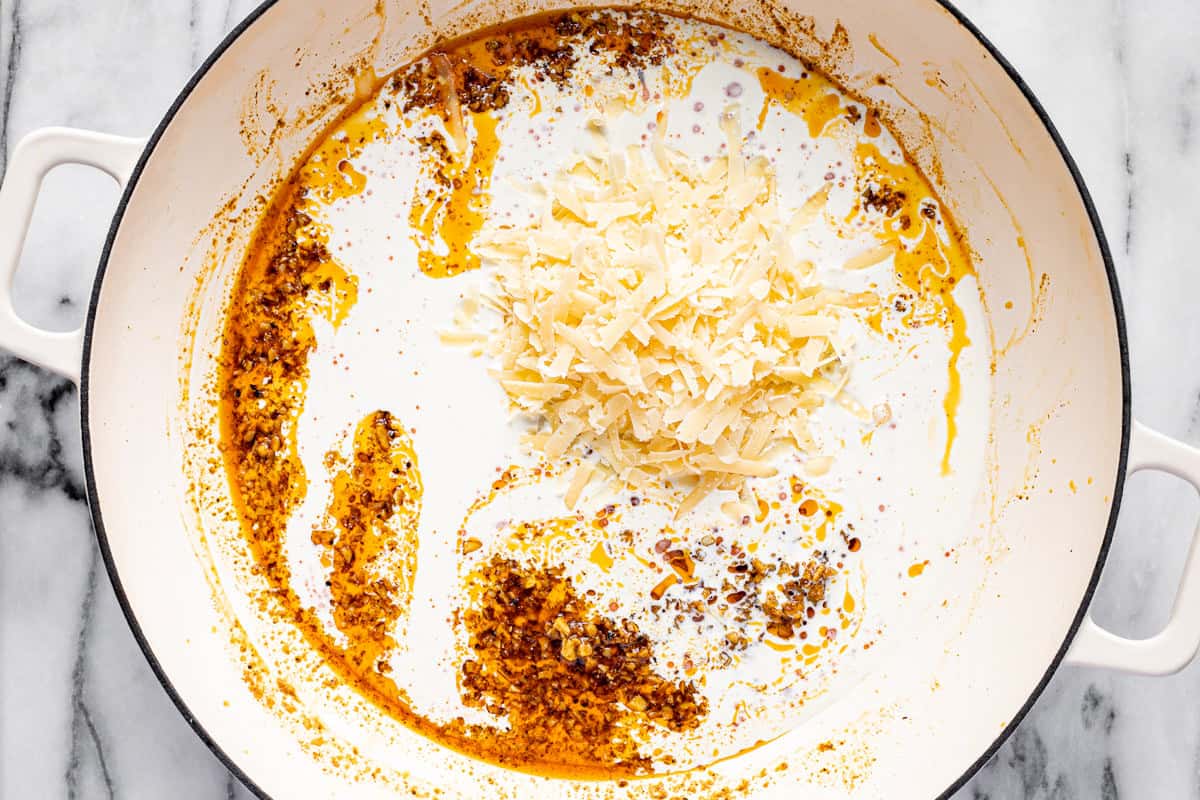 Ingredients to make creamy Cajun pasta sauce in a large white pan. 