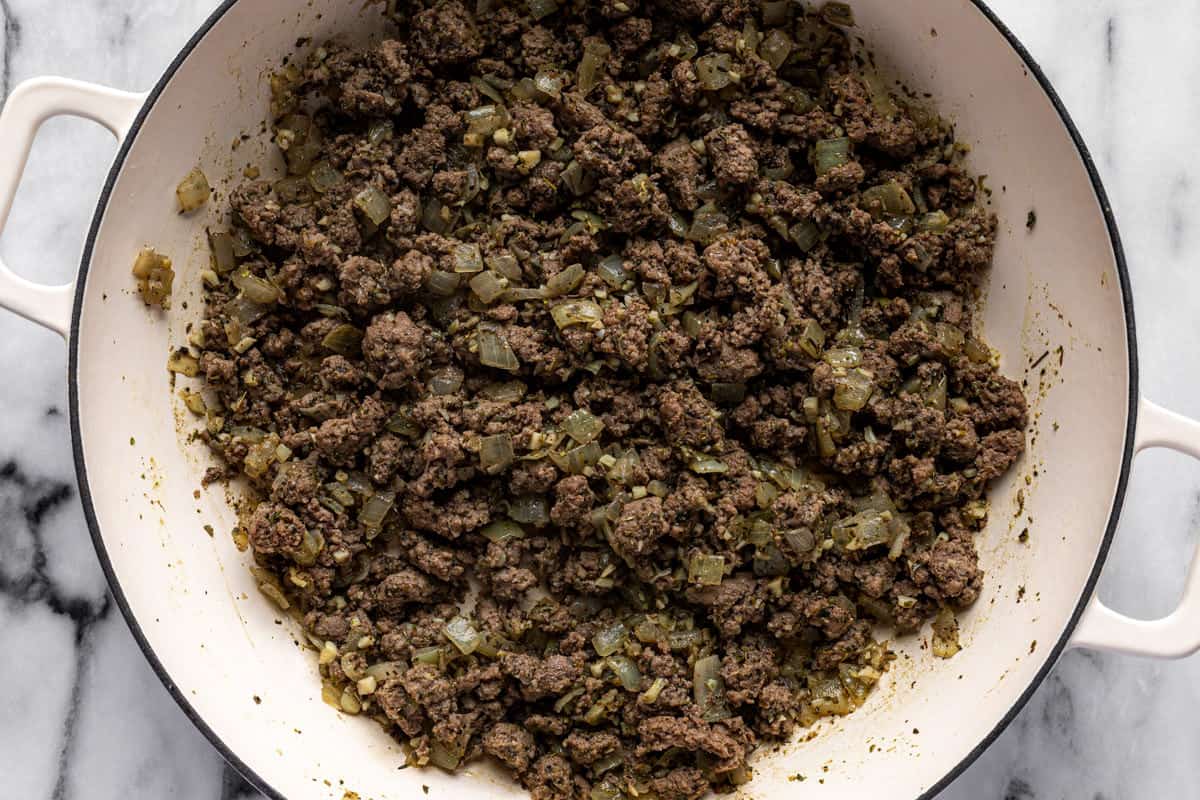 Browned ground beef with diced onions in a large saute pan. 