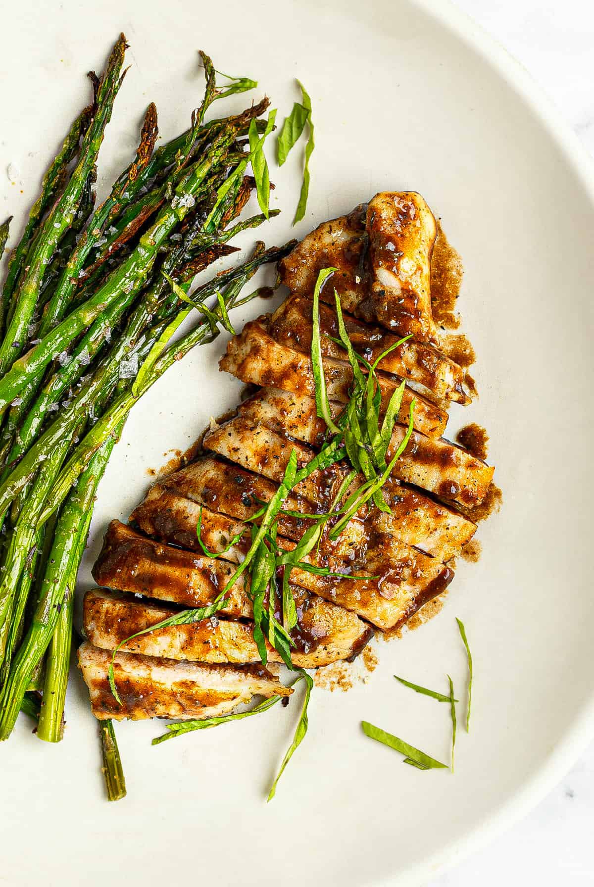 White plate with balsamic chicken and air fryer asparagus.