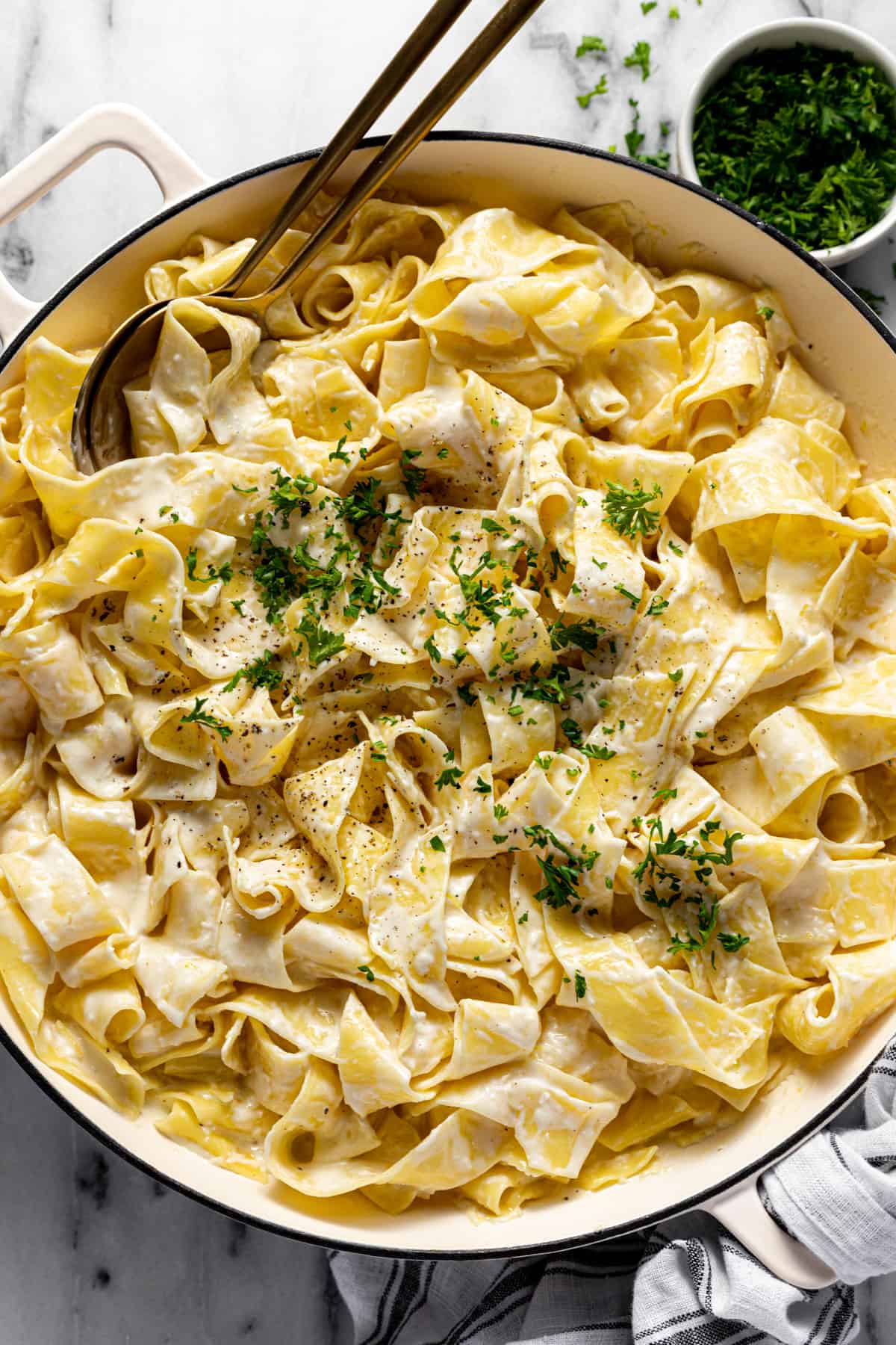 Large white pan filled with creamy lemon pasta garnished with parsley. 