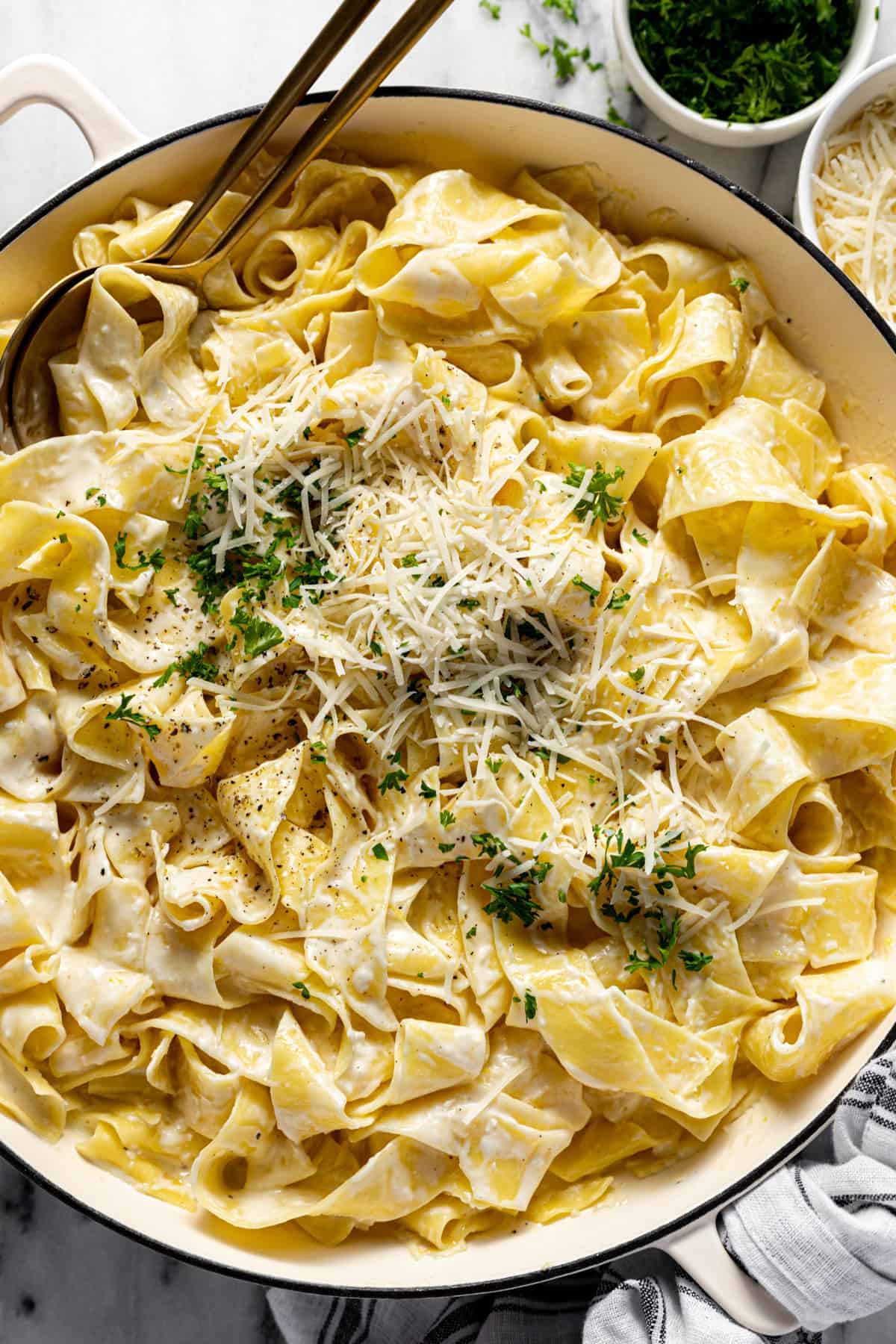 Large white pan filled with lemon pappardelle pasta garnished with Parmesan and parsley. 
