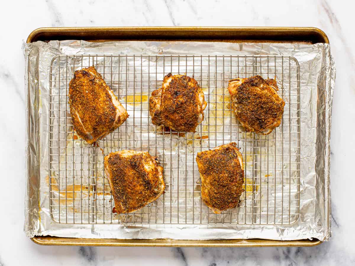 Large foil-lined baking sheet with juicy oven baked chicken thighs on it.